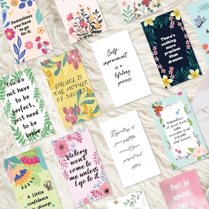 Flat lay of floral inspirational quote cards on a white plush rug for decoration