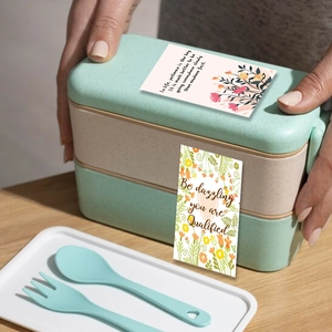 Close-up of double-layer lunch box with motivational quotes and floral stickers