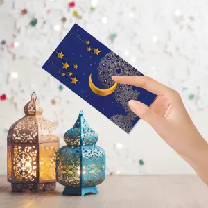 Detail of navy blue Eid envelope with gold crescent and mandala patterns in festive lighting