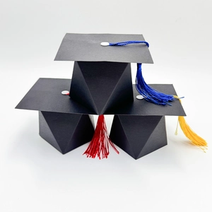 Macro detail of black graduation cap gift boxes with blue, red, and yellow silk tassels