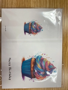 Detail of artistic rainbow cupcake birthday cards in plastic packaging on wooden table