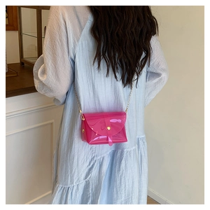 Detail van roze transparante jelly bag met gouden ketting op lichtblauwe jurk