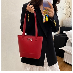 Vue détaillée d'un sac cabas rouge en cuir avec nœud argenté dans un décor de style