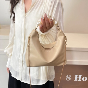 Beige mini dumpling bag featuring a large pearl handle and a slim gold chain strap