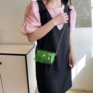 Groene transparante PVC-enveloptas met gouden ketting gedragen door model als crossbodytas
