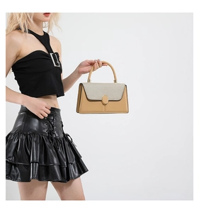 Detail of tweed flap and golden metal lock on light brown leather crossbody bag