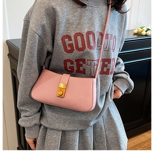 Detail of light pink shoulder bag featuring a premium gold twist lock buckle and slim strap