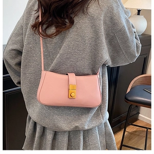 Rear view of a model wearing the light pink leather shoulder bag with a gold metal buckle