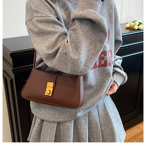 Detail of a vintage dark brown shoulder bag featuring a classic gold round buckle closure