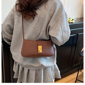 Detail of vintage brown leather underarm bag with elegant gold rectangular metal buckle