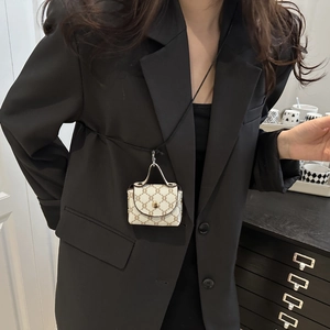 Detail of a mini monogram handbag charm with gold hardware hanging on a black suit