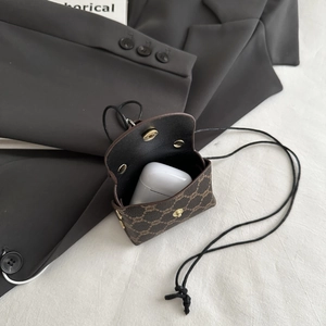 Macro detail of brown monogram mini earphone pouch with gold magnetic buckle and neck strap