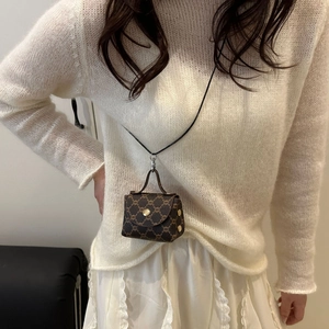 Mini brown monogram shoulder bag with gold clasp and cord strap on white knitwear