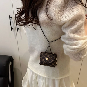 Close-up of a mini vintage pattern crossbody bag with golden buckle on white knitwear