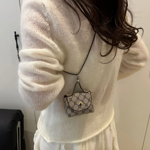 Detail of micro bag with vintage floral pattern and gold metal buckle on white outfit