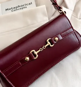Nahaufnahme der goldenen Trensen-Schnalle an einer tiefroten Vintage-Ledertasche