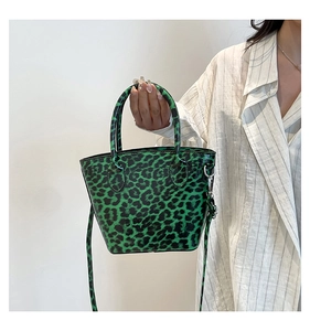 Dettaglio della borsa a secchiello leopardata verde e nera con fibbie in metallo e manici