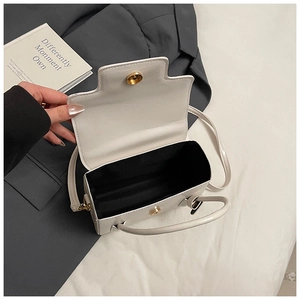 Detail showing white mini crossbody bag interior with gold magnetic clasp on grey blazer