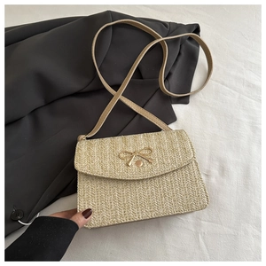 Détail du sac bandoulière tissé beige avec une boucle nœud dorée et fine bandoulière