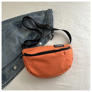 Macro view of bright orange sports crossbody bag with black FASHION label and zip detail