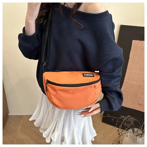 Detail of an orange nylon fanny pack with black zipper and fashion logo label
