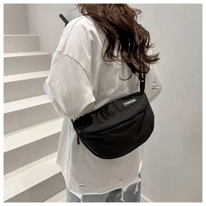 Detail of black nylon crossbody bag with fashion label on adjustable shoulder strap