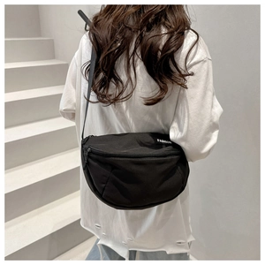 Close-up of minimalist black nylon crossbody bag with fashion tag on a female model