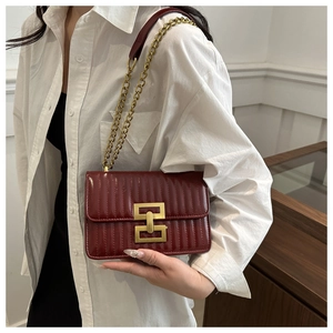 Détail d'un sac à bandoulière bordeaux avec fermoir H doré et texture matelassée