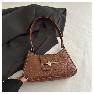 Detail of woven texture on brown leather handbag with silver star metal buckle