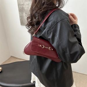 Retro weinrote Schultertasche mit goldener Trense, getragen von einem Model in schwarzer Lederjacke