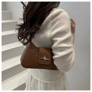 Detail of brown woven leather underarm bag with silver star-shaped metal clasp buckle