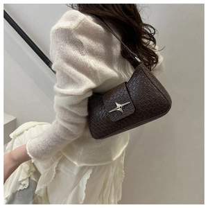 Detail of brown croc-embossed underarm bag with a silver star buckle on shoulder