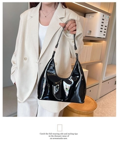 Detail of glossy black patent leather shoulder bag with elegant gold metal hardware
