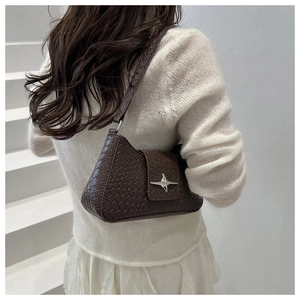 Detail of woven texture faux leather underarm bag with silver star buckle