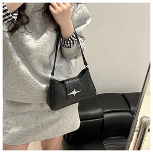 Close-up of black woven leather shoulder bag with a silver star buckle on model