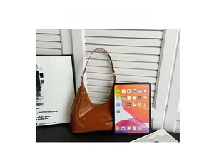 Brown patent leather hobo bag size comparison with tablet device for capacity view
