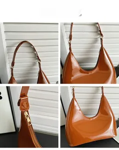 Detail view of brown patent leather hobo bag with metal buckle and smooth zipper