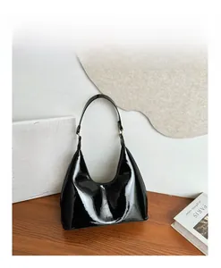 Close-up of shiny black patent leather hobo bag with sleek shoulder strap and metal hardware