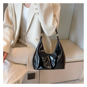 Glossy black patent leather hobo bag styled with a minimalist beige suit jacket