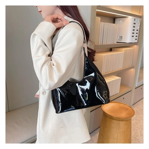 Close-up of black patent leather hobo bag with high-gloss finish and slim shoulder strap