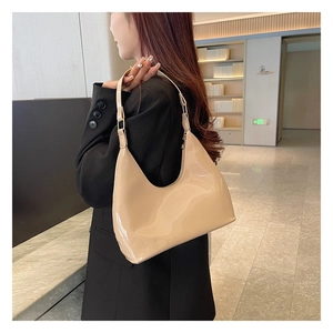 Close-up of beige patent leather shoulder bag with glossy finish and gold metal accents