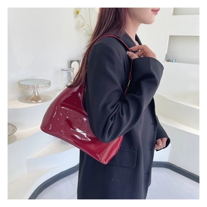 Detail of dark red patent leather hobo bag with glossy finish and minimalist shoulder strap