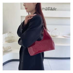 Detail of burgundy patent leather hobo bag with glossy finish and half-moon silhouette