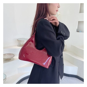 Detail of burgundy patent leather hobo bag showing high-gloss finish and sleek shoulder strap