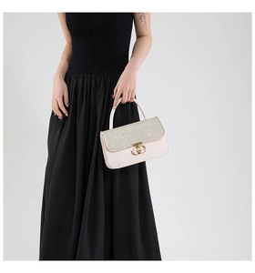 Close-up of sparkling sequined flap and golden horseshoe buckle on chic cream leather bag