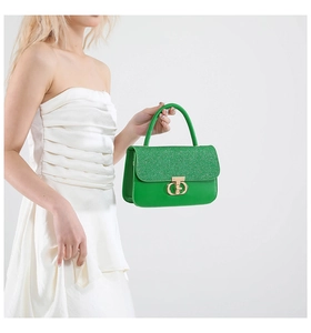 Detail of green handbag with glitter texture flap and elegant gold metal ring buckle