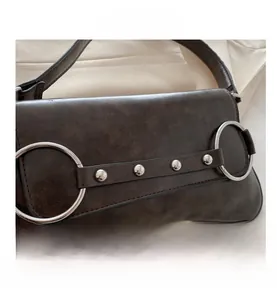 Détails d'un sac vintage marron foncé avec anneaux argentés et rivets décoratifs