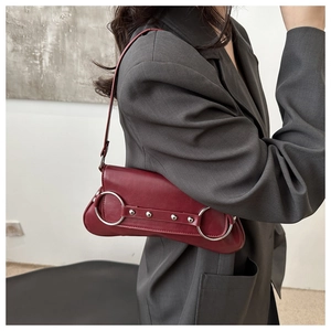 Détail d'un sac porté épaule bordeaux vintage avec anneaux argentés porté par un mannequin