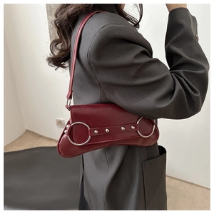 Détail du sac baguette bordeaux avec anneaux en métal argenté et clous décoratifs