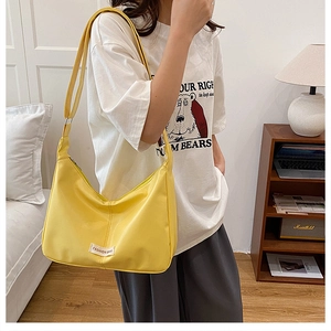 Lifestyle view of a yellow half-moon crossbody bag with adjustable strap and fashion label